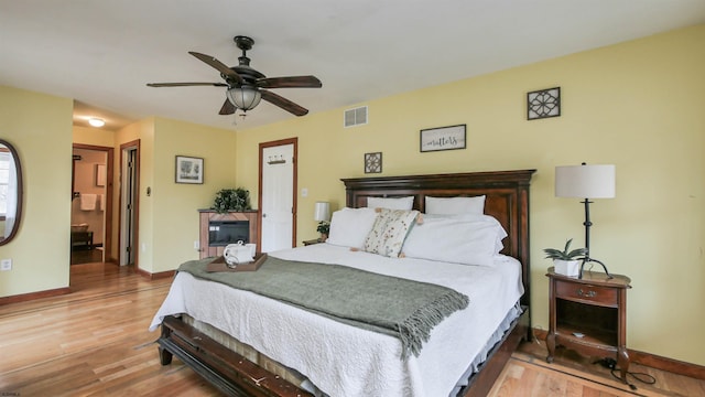 bedroom featuring a ceiling fan, baseboards, visible vents, and wood finished floors