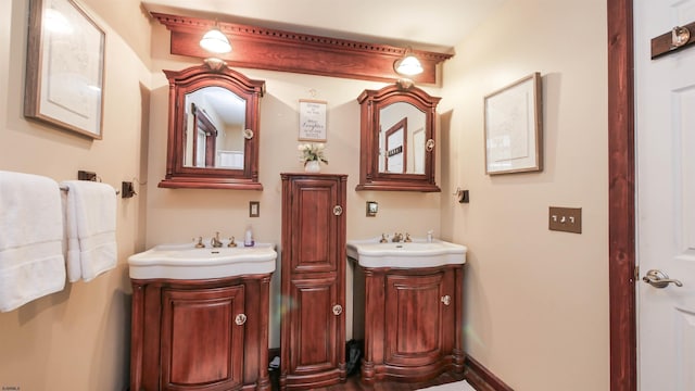 bathroom with two vanities, a sink, and baseboards