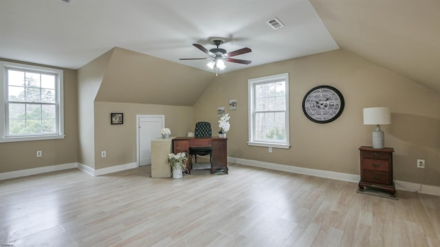 office space featuring light wood finished floors, baseboards, visible vents, and vaulted ceiling