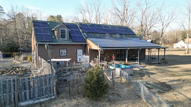 rear view of property with a shingled roof, fence, and solar panels