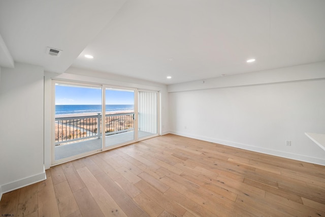 spare room featuring light wood-style flooring, recessed lighting, a water view, visible vents, and baseboards