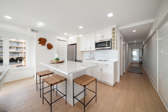 kitchen featuring visible vents, a kitchen bar, appliances with stainless steel finishes, and light wood-style flooring