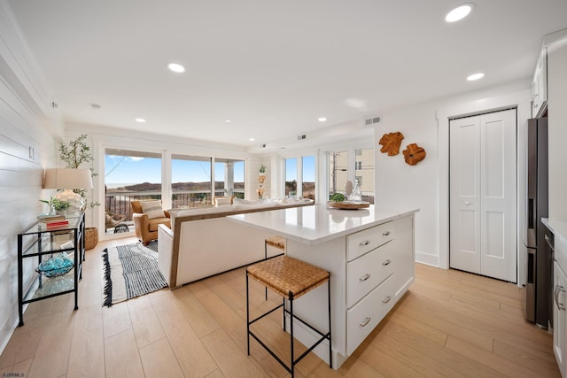 kitchen with a breakfast bar, a center island, light wood finished floors, light countertops, and open floor plan