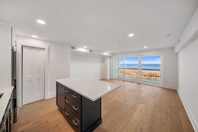 kitchen featuring visible vents, baseboards, a center island, light wood-style floors, and recessed lighting
