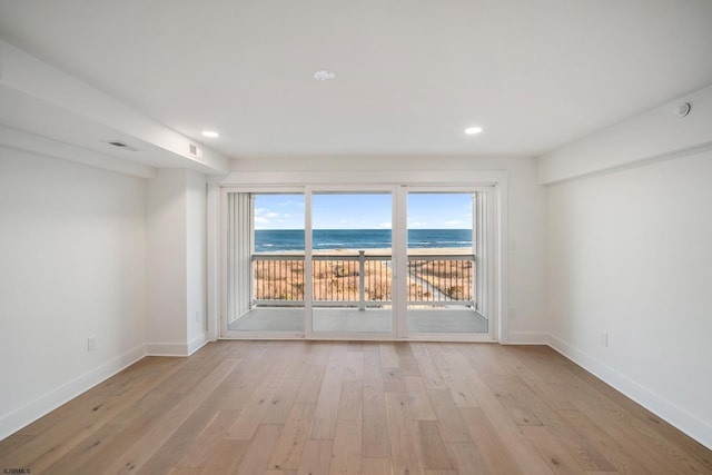 unfurnished room featuring recessed lighting, visible vents, a water view, light wood-style flooring, and baseboards