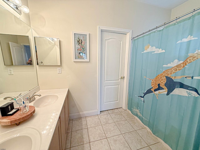 bathroom featuring double vanity, tile patterned flooring, a sink, and baseboards