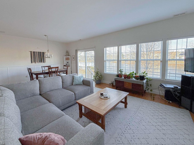 living room featuring a wainscoted wall, wood finished floors, and visible vents