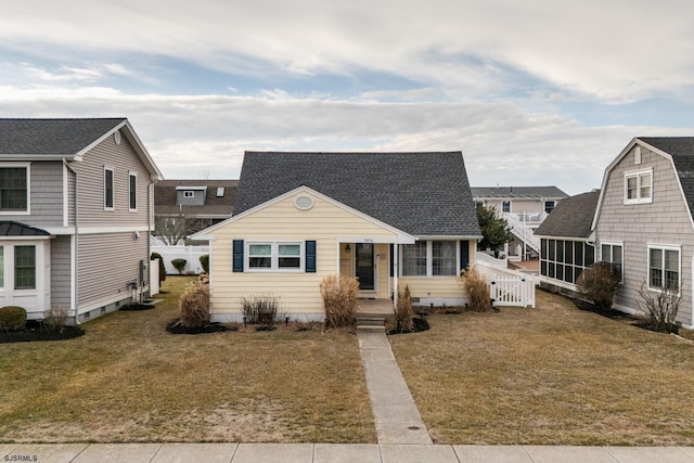 view of front of home featuring roof with shingles and a front yard