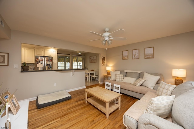 living area with ceiling fan, light wood finished floors, and baseboards