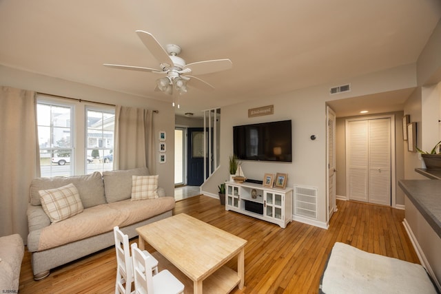 living area featuring light wood finished floors, baseboards, visible vents, and a ceiling fan