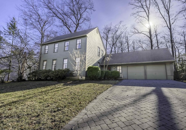 colonial inspired home featuring an attached garage, a front lawn, and decorative driveway