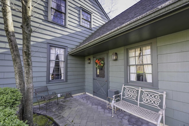 entrance to property with a patio and roof with shingles