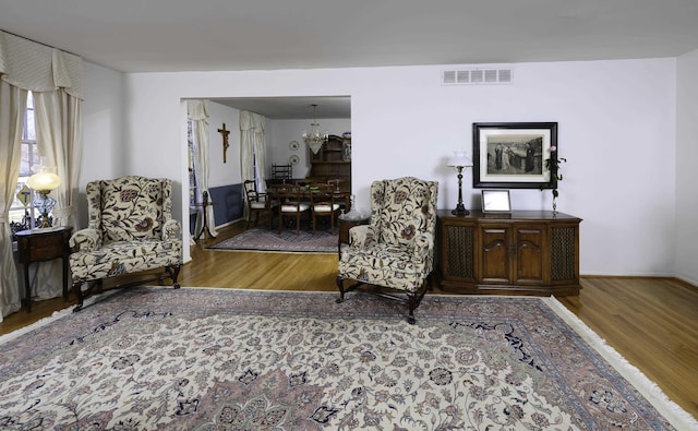 sitting room featuring an inviting chandelier, baseboards, visible vents, and wood finished floors