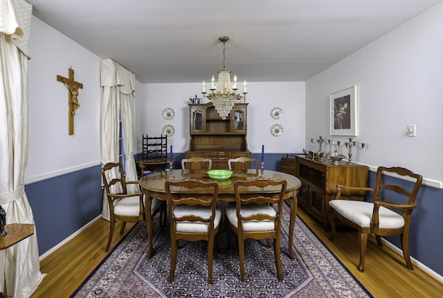 dining room with baseboards, a notable chandelier, and wood finished floors