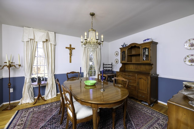 dining area featuring an inviting chandelier, baseboards, and wood finished floors