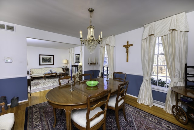 dining room with visible vents, a notable chandelier, baseboards, and wood finished floors