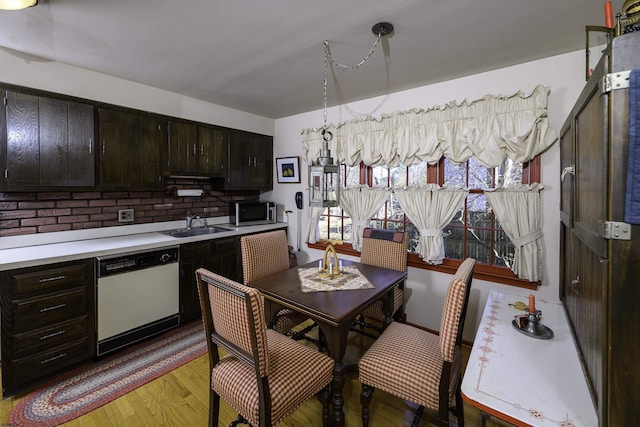 kitchen with a sink, light countertops, light wood-type flooring, dishwasher, and stainless steel microwave