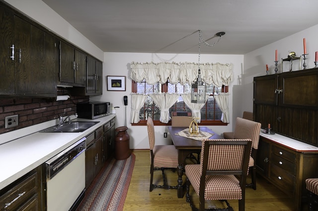 kitchen with white dishwasher, a sink, light countertops, light wood-type flooring, and stainless steel microwave