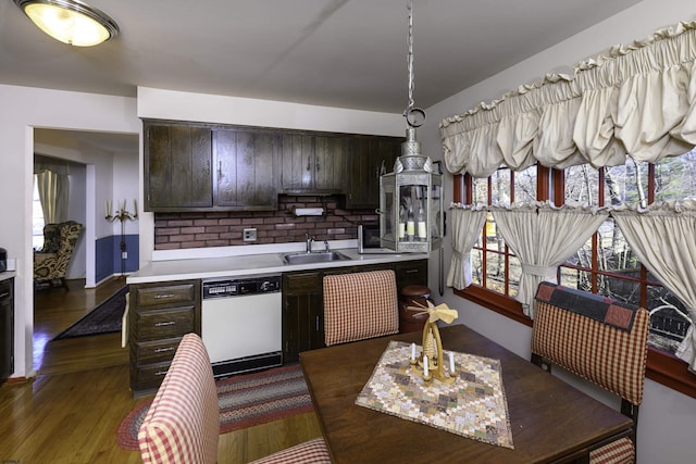 kitchen with light countertops, decorative backsplash, dark brown cabinetry, white dishwasher, and a sink