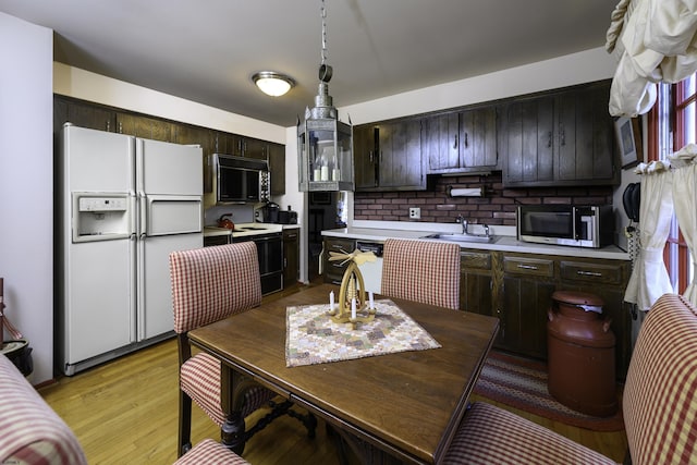 kitchen featuring black microwave, electric range, white refrigerator with ice dispenser, light countertops, and stainless steel microwave