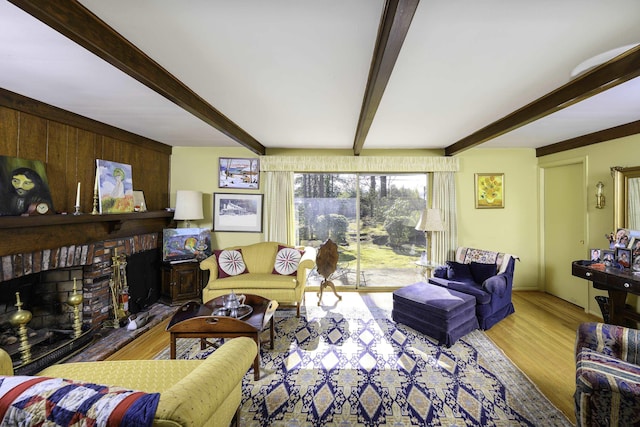 living room with a brick fireplace, beam ceiling, and wood finished floors