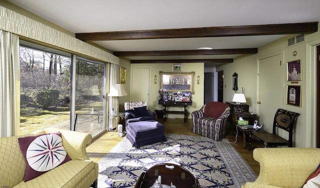 living area featuring light wood-style flooring, visible vents, and beamed ceiling