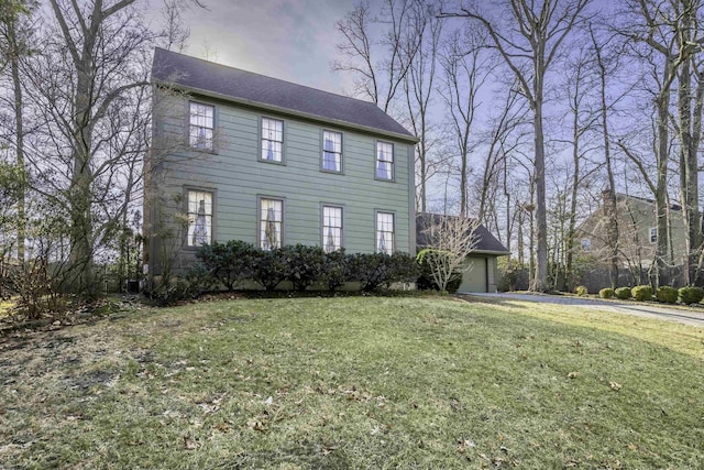 colonial home with an attached garage and a front lawn