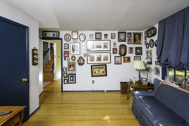 living area with light wood-style flooring, stairway, and baseboards