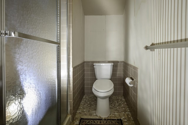 full bath featuring wainscoting, toilet, tile patterned flooring, a shower stall, and tile walls