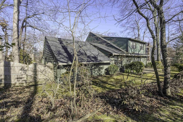 view of property exterior featuring fence and roof with shingles