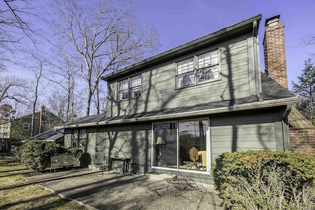 rear view of property featuring a patio area and a chimney