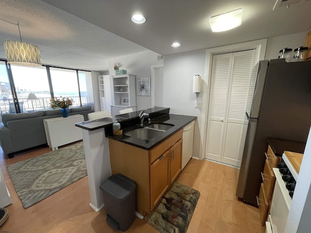 kitchen with dishwasher, dark countertops, open floor plan, a peninsula, and a sink