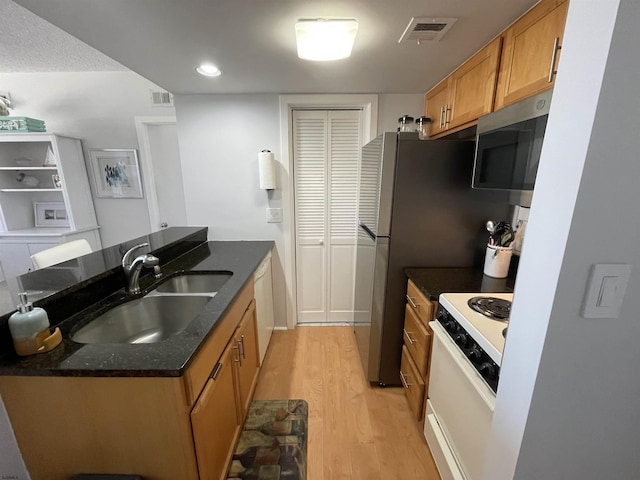 kitchen featuring white appliances, light wood-style flooring, a sink, and visible vents