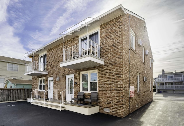 exterior space with brick siding, crawl space, fence, and a balcony