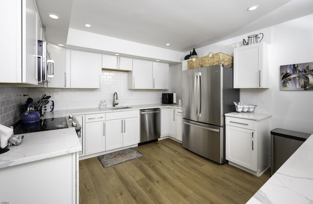 kitchen featuring a sink, stainless steel appliances, wood finished floors, and white cabinets