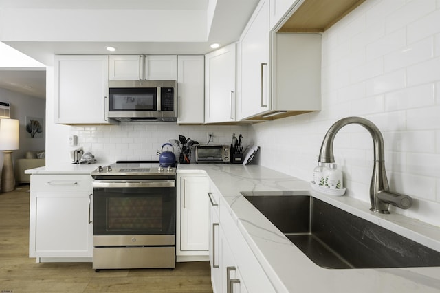 kitchen with white cabinetry, tasteful backsplash, appliances with stainless steel finishes, and a sink