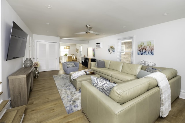 living room featuring an AC wall unit, wood finished floors, and a ceiling fan