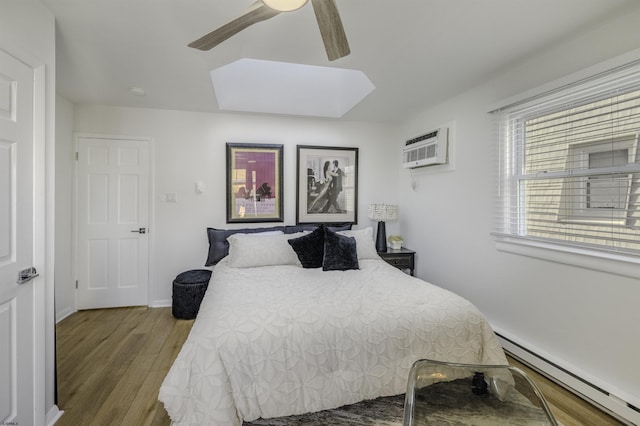 bedroom with a baseboard radiator, a wall mounted AC, a ceiling fan, wood finished floors, and baseboards