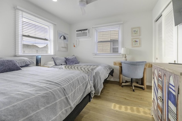 bedroom with an AC wall unit, multiple windows, a closet, and light wood-style flooring