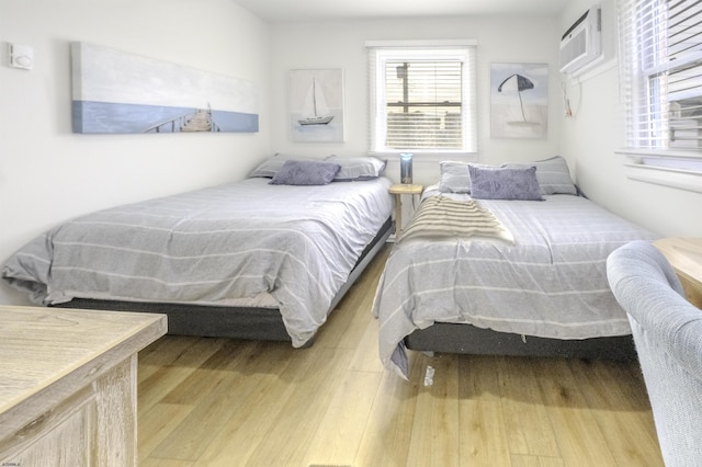 bedroom with a wall unit AC and wood finished floors