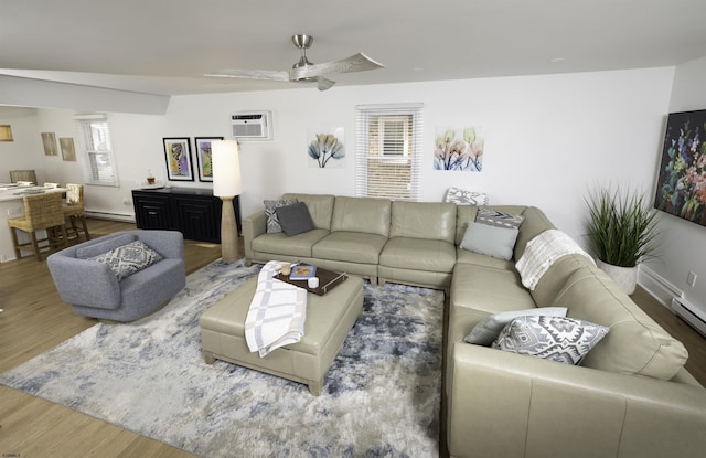 living area with a baseboard heating unit, a wall mounted air conditioner, wood finished floors, and a ceiling fan