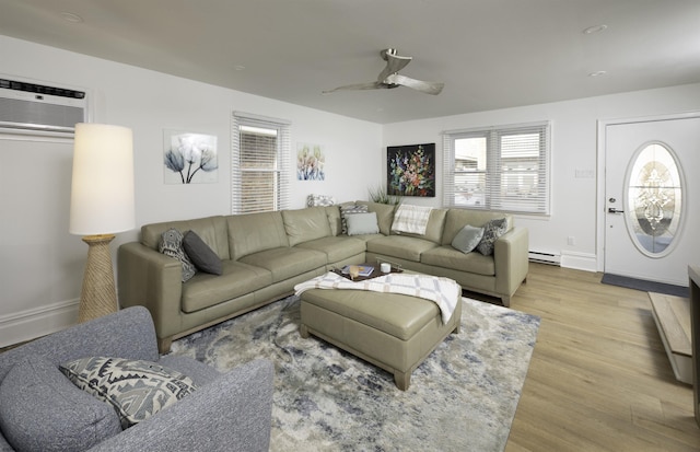 living area featuring baseboards, a ceiling fan, a baseboard radiator, wood finished floors, and an AC wall unit