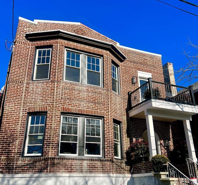 exterior space featuring brick siding and a balcony