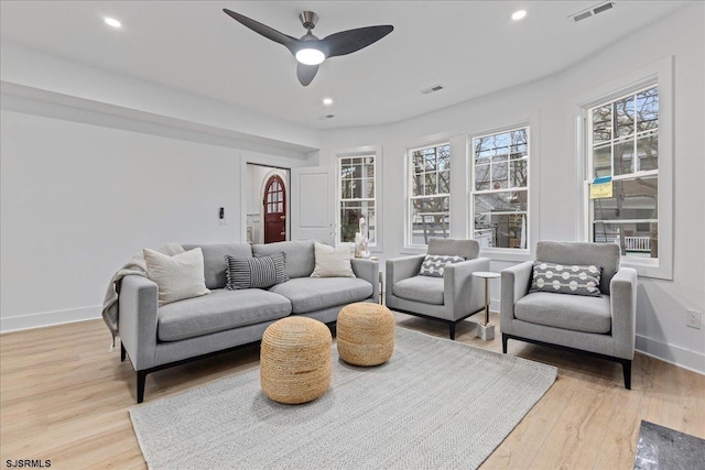 living area with baseboards, visible vents, and light wood-style floors