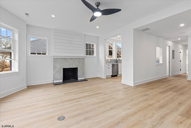 unfurnished living room featuring recessed lighting, a sink, a high end fireplace, visible vents, and light wood-type flooring