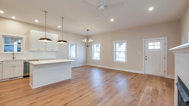 kitchen with white cabinets, light countertops, a sink, and stainless steel dishwasher