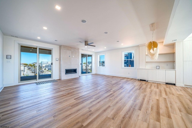 unfurnished living room featuring recessed lighting, light wood-style flooring, ceiling fan, a tile fireplace, and baseboards