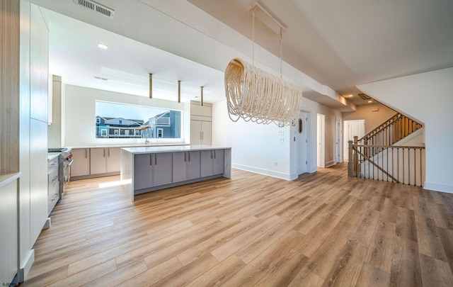 kitchen featuring light countertops, light wood-type flooring, a kitchen island, and visible vents