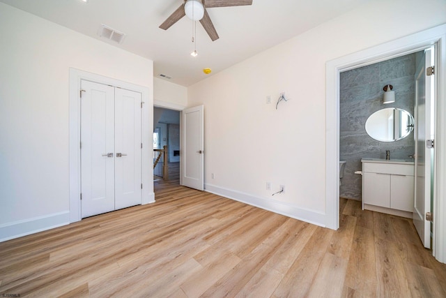 unfurnished bedroom with light wood finished floors, a closet, visible vents, ensuite bathroom, and baseboards