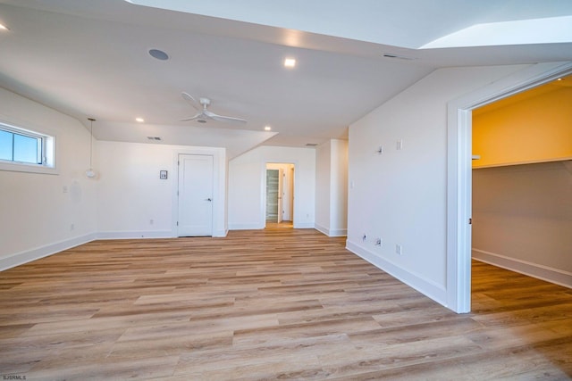 empty room with vaulted ceiling, light wood-style flooring, and baseboards